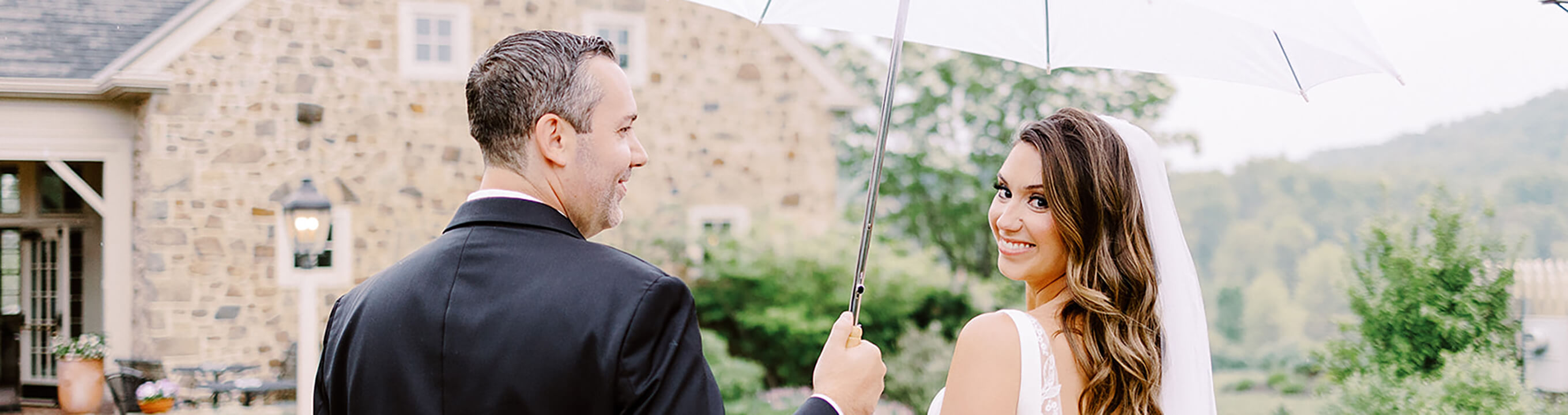 groom holds umbrella for bride